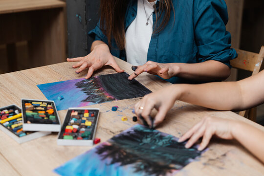 Creative individuals engaged in pastel art at a wooden table