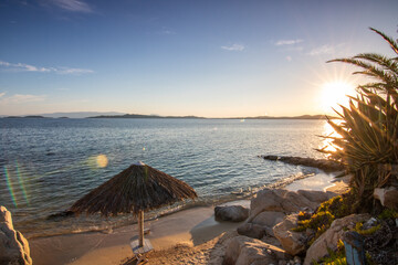 View through rocks on a sandy beach into the sunset. Landscape shot with a view to the horizon over...