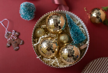 Christmas decorations in the round gift box with fir tree on the red background. Close up winter holidays greeting card.