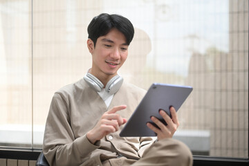 A young man uses a tablet, exemplifying modern digital learning in a comfortable setting