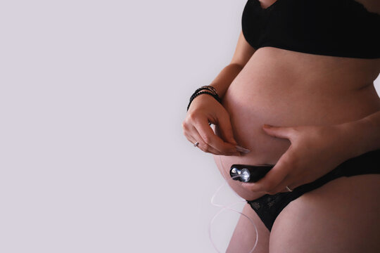 Pregnant woman removing infusion set from belly while holding insulin pump
