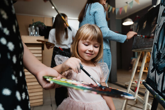 Girl painting on canvas during a creative art class in the studio