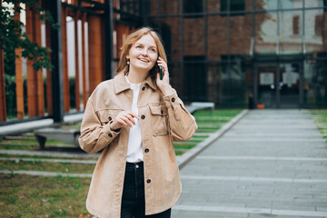 Fototapeta premium Happy 30s woman talking phone and look happy outdoors. Urban lifestyle concept. Summer time. Beautiful woman walking on the city street.