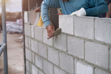 masonry worker make concrete wall by cement block and plaster at construction site             
