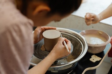 A potter crafting a ceramic cup at a studio during a pottery class