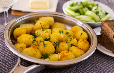 Toasted young potatoes with dill in metal skillet