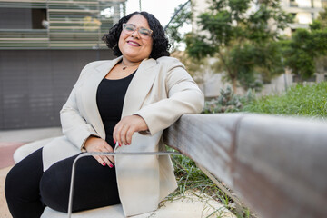Happy woman sitting outdoors in a smart casual outfit