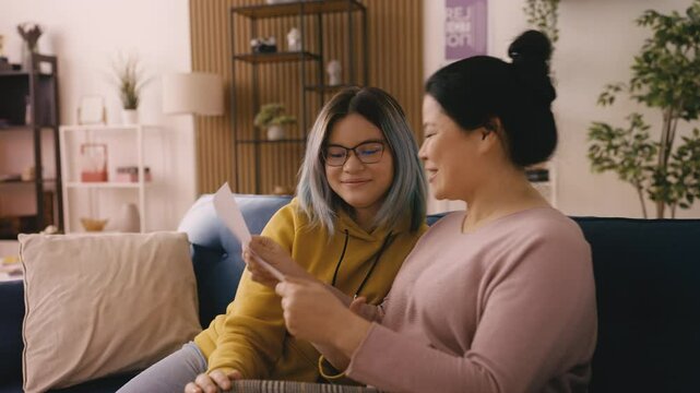 Happy Asian teen girl showing an A grade for school test to her mom, achievement