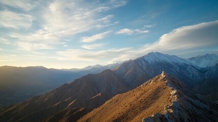 Obraz premium Rugged mountain peaks tower dramatically, featuring jagged cliffs and snow-capped summits, illuminated by sunlight breaking through clouds in a breathtaking sunset