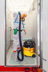 Asbestos surveyor with a ventilated mask and a protective Hazmat suit in a mobile decontamination...