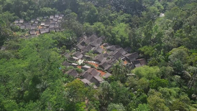 Drone view the traditional houses of the Baduy Tribe are neatly arranged amidst the green forest and flowing rivers, located in Kanekes Village, in the interior of Lebak Regency, Banten, Indonesia.