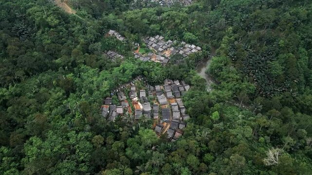 Drone view the traditional houses of the Baduy Tribe are neatly arranged amidst the green forest and flowing rivers, located in Kanekes Village, in the interior of Lebak Regency, Banten, Indonesia.