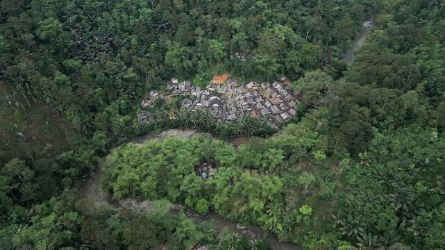 Drone view the traditional houses of the Baduy Tribe are neatly arranged amidst the green forest and flowing rivers, located in Kanekes Village, in the interior of Lebak Regency, Banten, Indonesia.