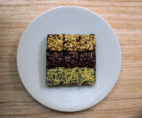 brownie cake with chocolate topping, nuts and cheese, on a white plate