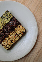 brownie cake with chocolate topping, nuts and cheese, on a white plate