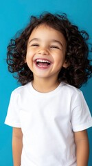 a happy, laughing child with curly hair, wearing a white t shirt against a blue background