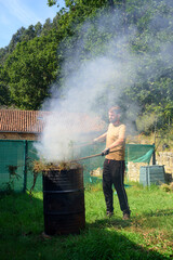 Hombre joven barbudo quemando poda en su jardín