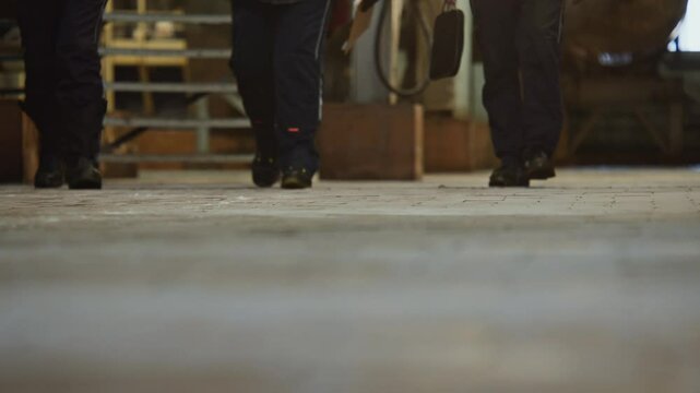 Close-up of workers' feet walking on the tiled floor of a factory.