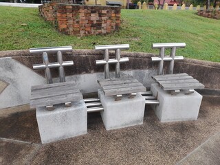 Uniquely designed outdoor chairs with stainless steel backs and wooden seats, set against a...