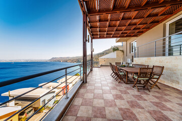 outdoor terrace with wooden pergola and panoramic sea view. The serene setting and natural wooden elements create relaxing atmosphere, perfect for enjoying sea backdrop