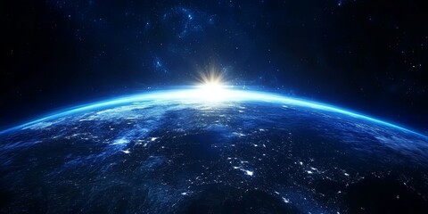 Sunrise over Earth as seen from space.  The sun is rising on the horizon of the planet, illuminating the atmosphere with a golden glow.