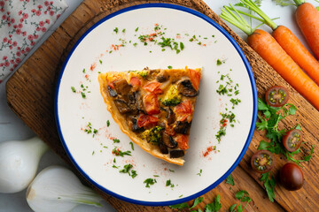 Piece of roasted vegetarian vegetable quiche. Top view table with decorations.