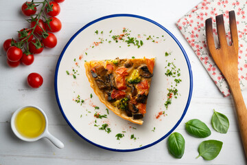 Piece of roasted vegetarian vegetable quiche. Top view table with decorations.