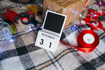 Calendar with December 31 date on a cozy plaid blanket with Christmas toys. New Year eve preparation