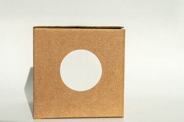 Brown cardboard box with white circular sticker on a neutral background.
