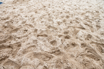 Footprints and textured sand on the beach. Close-up of sandy surface with human impressions