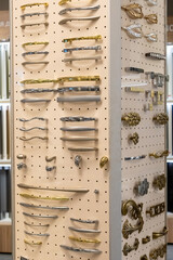 Display of assorted cabinet handles and knobs on pegboard. Interior design and hardware selection.