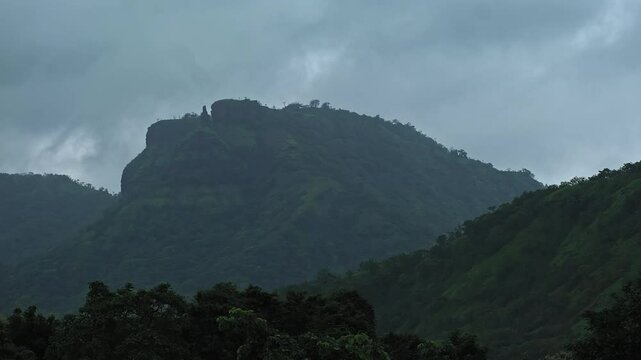 A timelapse of clouds moving behind a mountain during the monsoon season in Maharashtra, India.
