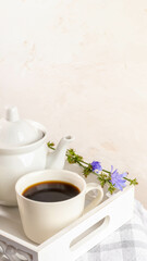 White cup and teapot with chicory tea on white wooden tray. Best alternative for coffee. Copy space.