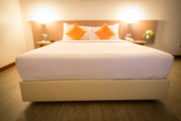 Blurred image of a hotel bedroom with 2 orange pillows, modern and minimalist decor. The bed is soft, clean, good atmosphere
