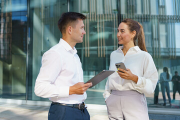 Business Professionals Engage in Conversation Outside a Modern Office Building During Daylight Hours