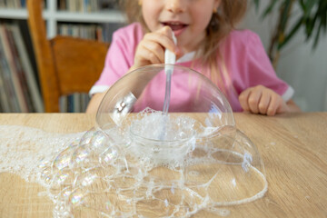 Little girl blows bubbles made of soap foam, bursts, kids fun games, diy soap bubbles, making...