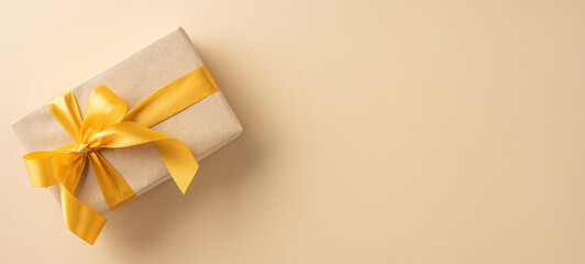 A beautifully wrapped gift box with a golden ribbon, set against a neutral beige background, conveying elegance and celebration