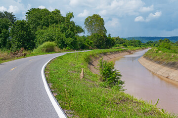 Irrigation canal along the small asphalt road in agriculture area, countryside of Thailand