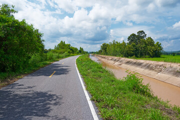 Irrigation canal along the small asphalt road in agriculture area, countryside of Thailand