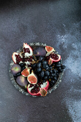 Autumn fruits on dark background: figs, grapes, pomegranate. Close up. Place for text