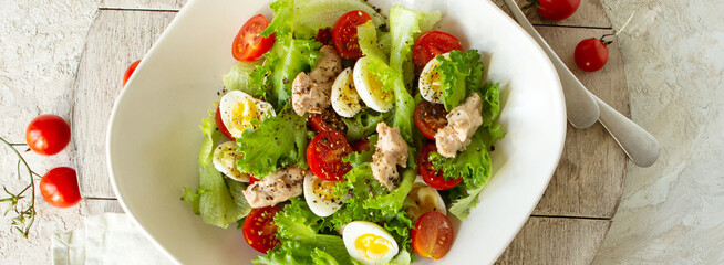 bowl of salad with cod liver, quail eggs and cherry tomatoes on the table