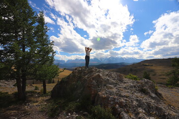 Hiker woman on top Aktash Altai mountains. Scenic view and snowy tops on background.
