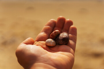 Stones on the palm of the hand against the background of yellow sand