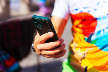 A person in a colorful shirt is holding a cell phone
