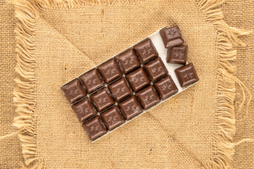 Dark chocolate on a jute cloth, macro, top view.