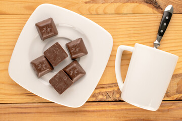 Dark chocolate with ceramic dishes on a wooden table, macro, top view.