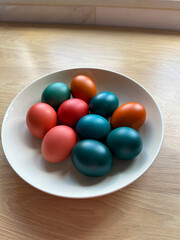 Bowl of vibrant colored Easter eggs standing on a wooden surface, beautifully festive and joyful atmosphere. Easter and religious holidays