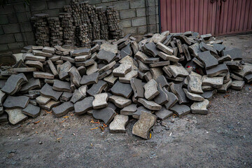 A large stack of unbroken concrete pavers neatly piled in an outdoor space, likely for construction or landscaping purposes. The pavers are ready for use in paving roads, sidewalks, or patios.

