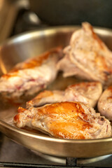 Portions of rabbit meat are fried in a frying pan closeup