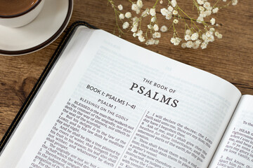 Psalms open holy bible book with coffee cup on wooden table. Studying and reading old testament...